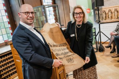 Bürgermeister Michael Gerdhenrich überreicht den Beitrag der Stadt Beckum für das entstehende Haus der Geschichte, einen Jute-Zementsack aus den 1920-er Jahren, an Dr. Gabriele Uelsberg.