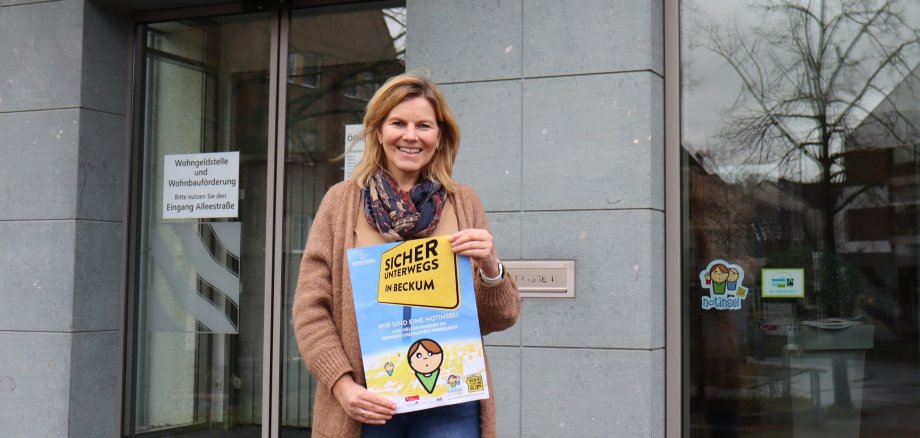 Silke Knipping  hält das Plakat vor dem Rathauseingang hoch